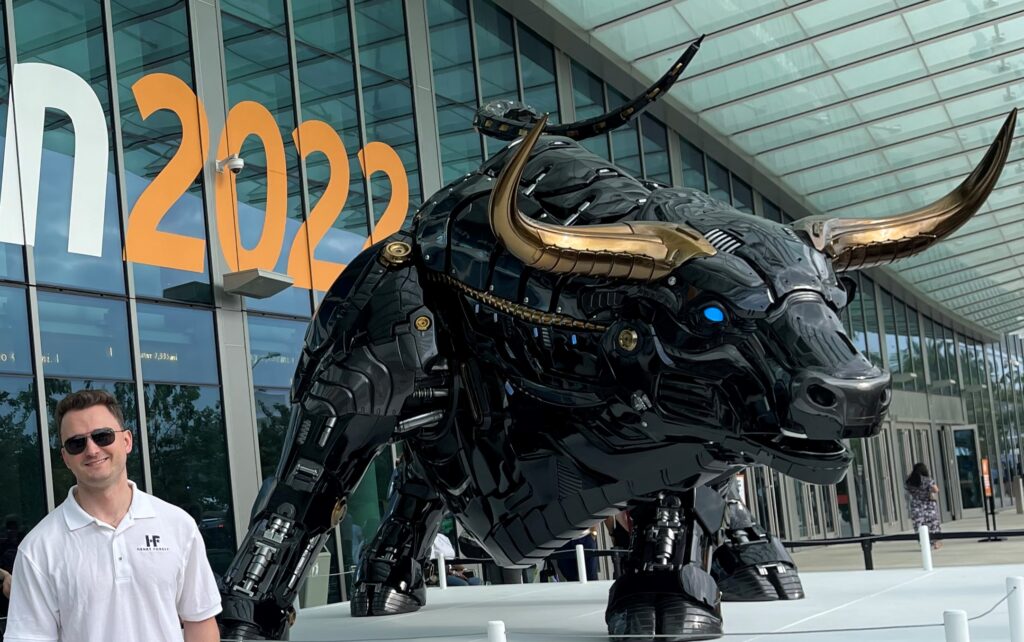 A man wearing a white top and sunglasses while standing beside the statue of a bull
