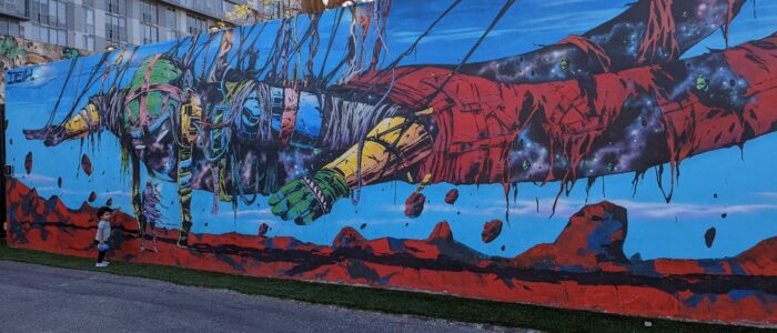 small kid standing in front of a painted wall