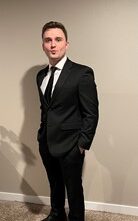 A man wearing a black suit and tie