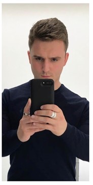 A man wearing a navy-blue top while holding a black phone